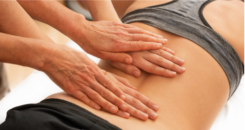 two sets of hands massaging a womans back