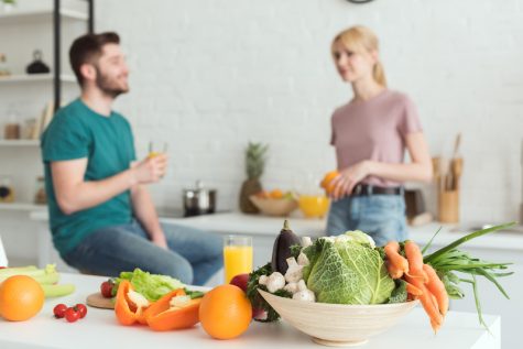 fruits and vegetables in foregoround, man and woman talking in background