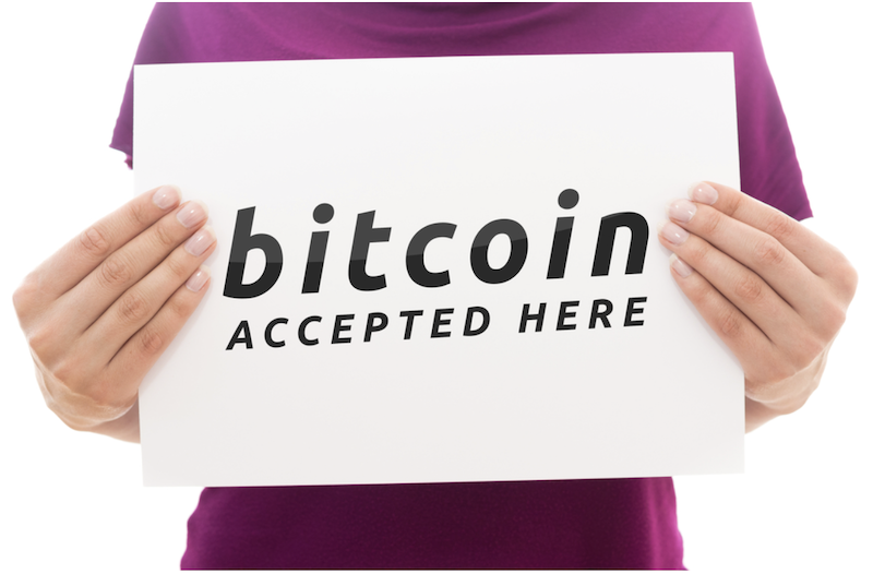 person+in+a+purple+shirt+holding+a+sign+that+says+Bitcoin+accepted+here