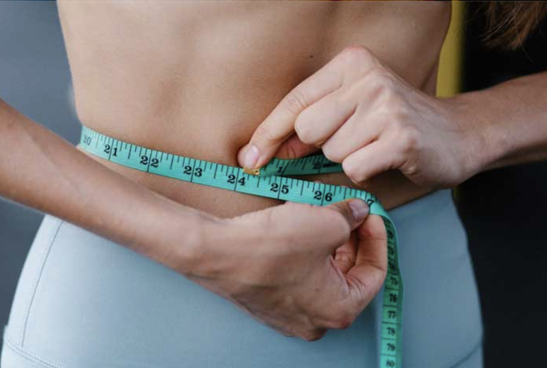 A+woman+measuring+her+abdomen