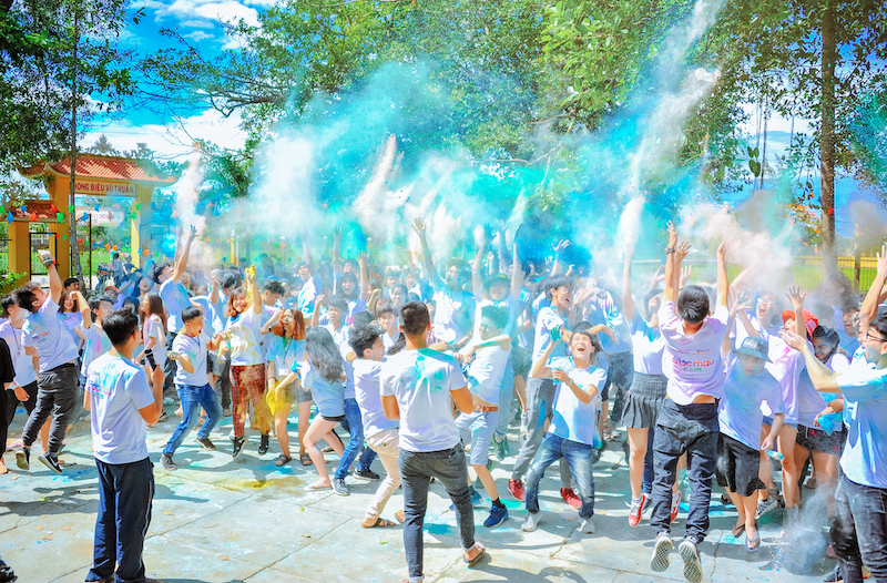 male and female student wearing white shirts throwing colorful sand