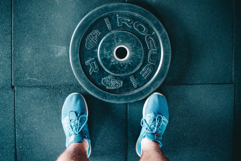 overhead view of dumbbell weight and feet wearing blue sneakers