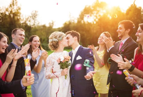 bride and groom kissing at wedding while surrounded by clapping guests
