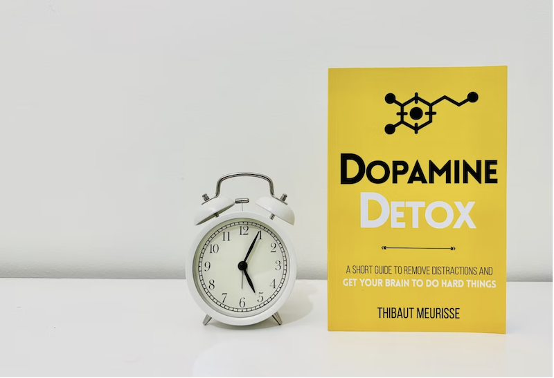 white+alarm+clock+and+yellow+book+titled+Dopamine+Detox