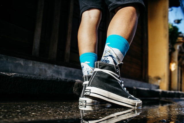 close-up of legs of a person wearing black sneakers and blue/white socks