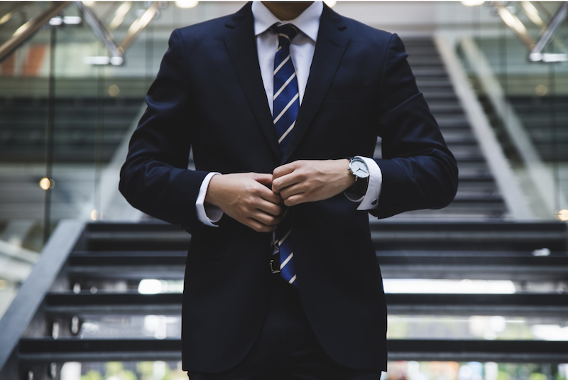 cropped shot of a man buttoning a navy blue suit
