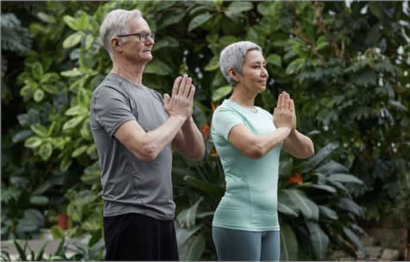 Older man and woman standing outside holding prayer hands to heart