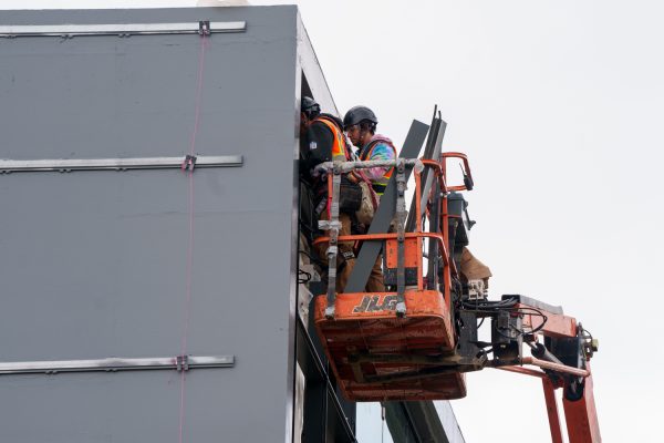 Workers inspect the placement of glass panels on the nearly completed Sierra Annex, Maple Hall, Thursday March 16, 2023.