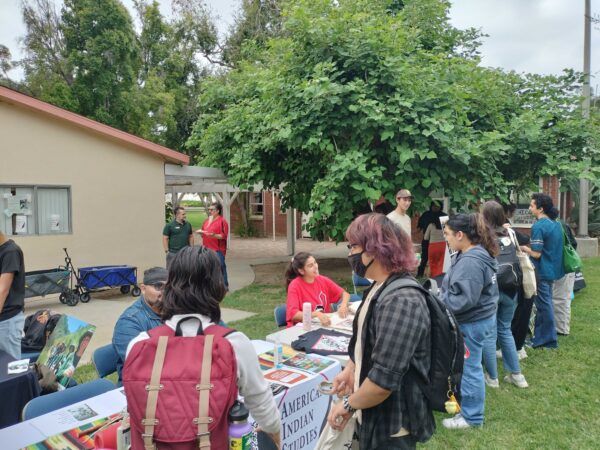 Attendees of the Native American Welcome event receive information from the CSUN American Indian Studies booth on Sept. 20, 2023, in Northridge, Calif.