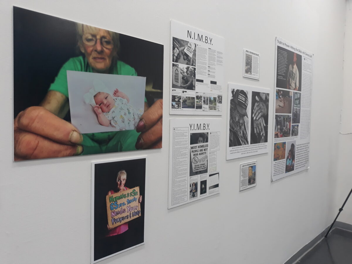 Some of the photos on display at the Skid Row History Museum & Archive in Los Angeles, Calif., on Sept. 16, 2023. Gracie (left) holds up a photo of a baby above a sign that says Homeless 65 Yrs. Really Needs Your Prayers & Help.