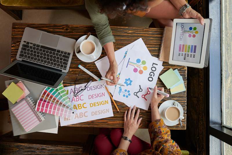 Hands of creative women choosing logo for start-up project