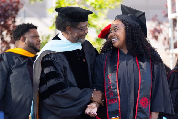 A student shakes the hand of William Watkins, Vice President for Student Affairs and Dean of Students, during the Black Graduation on the University Library Lawn on Sunday, May 12, 2024.