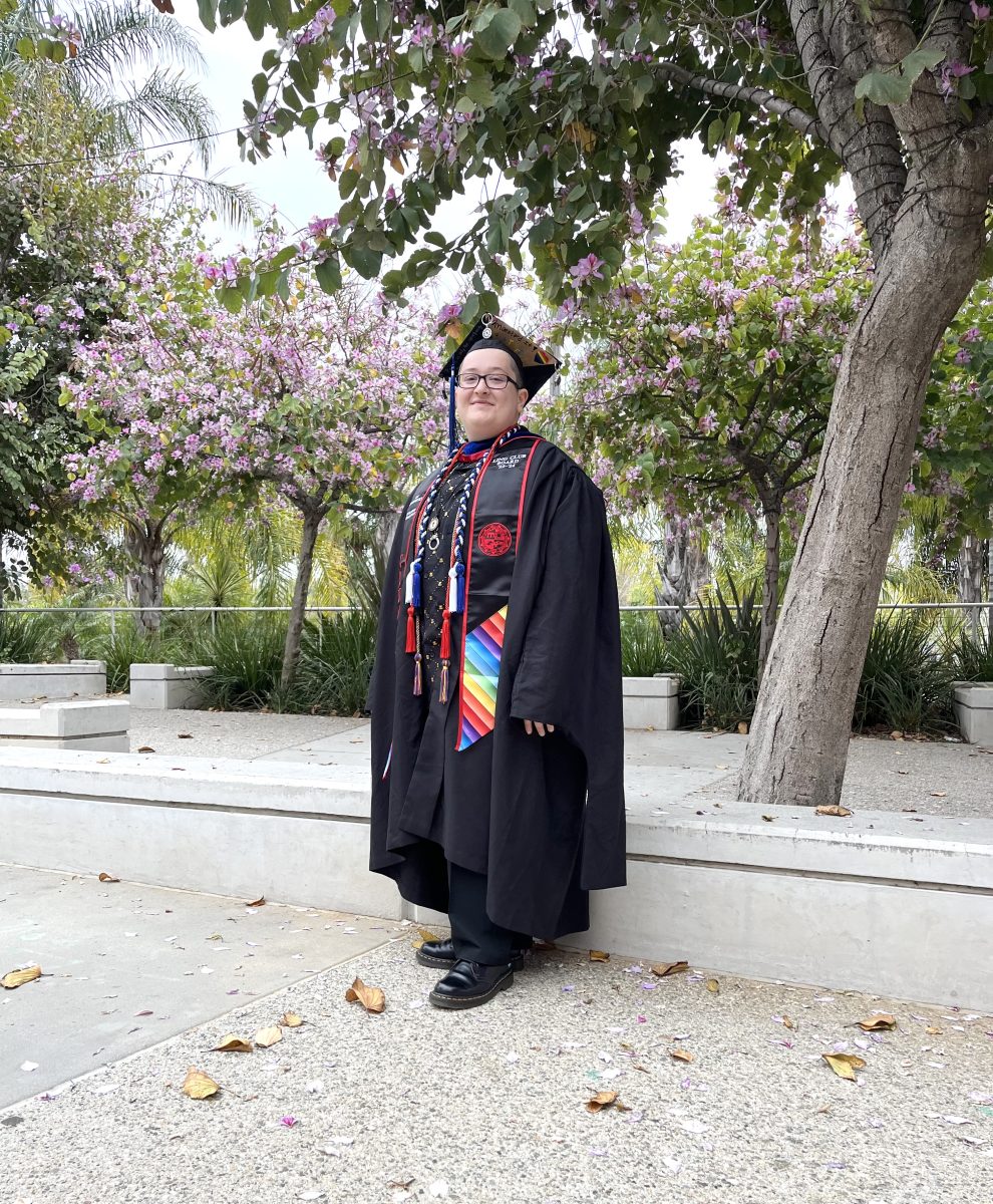 Silas Klein, linguistics masters graduate, wears graduation finery with added Pride adornments for Rainbow Graduation on Friday, May 17, 2024 in Northridge, Calif.