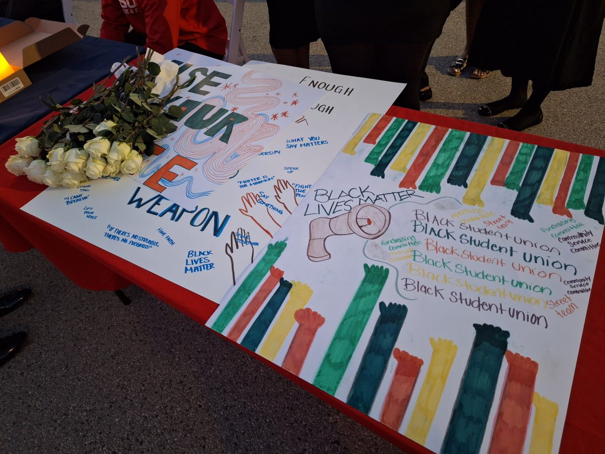 Posters and roses decorate a table as Black Student Union students and members pass out candles for attendees as they arrive at the Candlelight Ceremony for Marcellus Williams in Plaza Del Sol on Oct. 29.