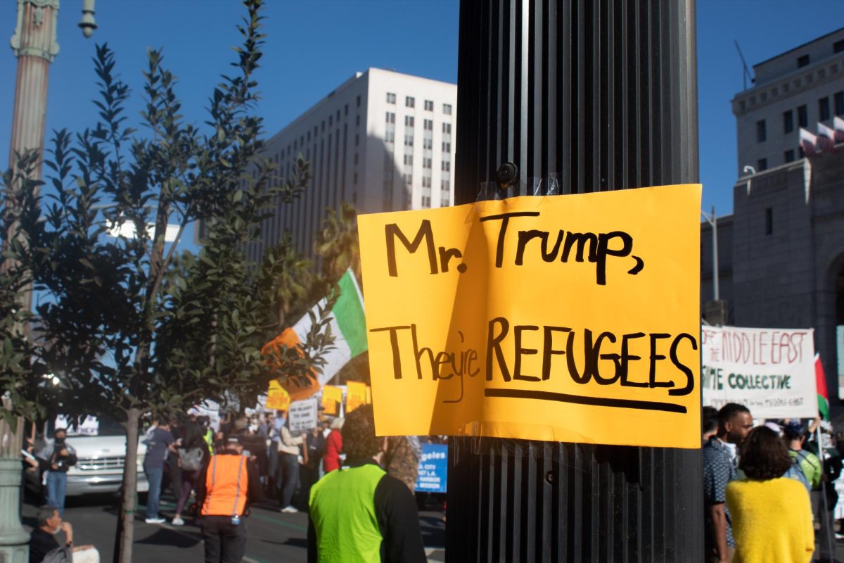 Sign hung up in front of Los Angeles City Hall on light pole by protester as marchers gather on Spring Street on Monday, Jan. 20, 2025.