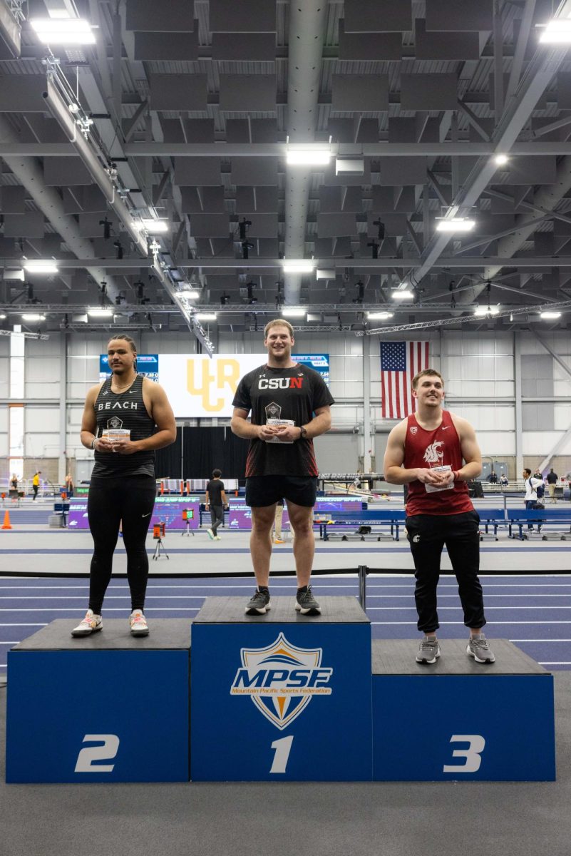 Three men standing on podium that are labeled number one, two, three