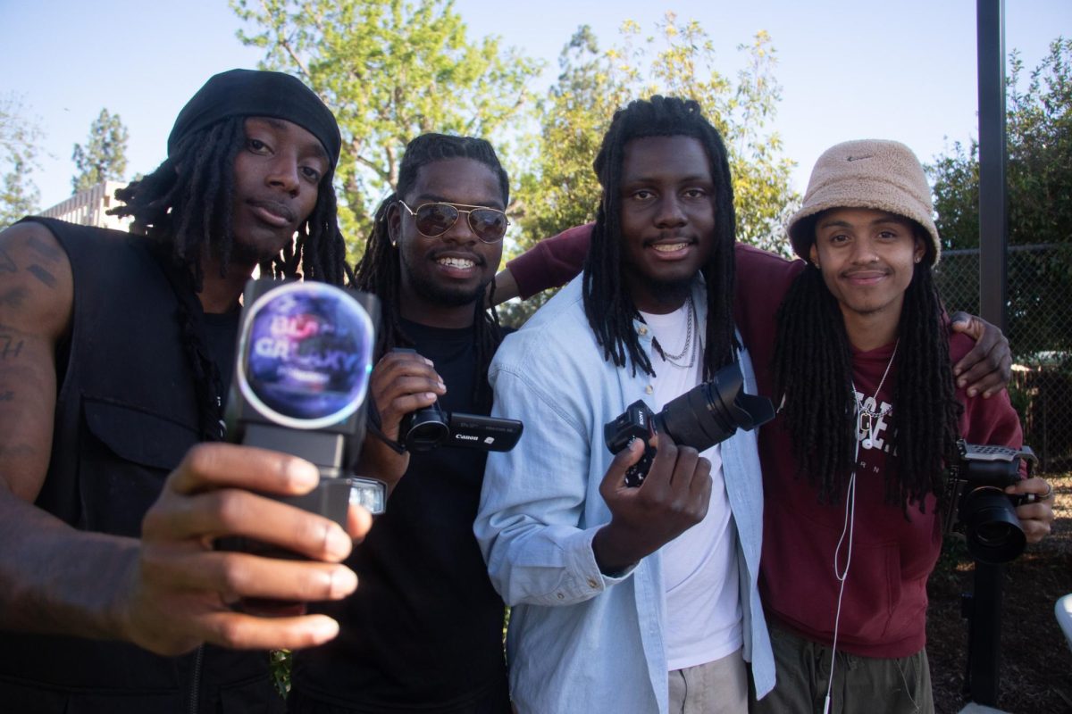 Four men standing next to each other holding black cameras