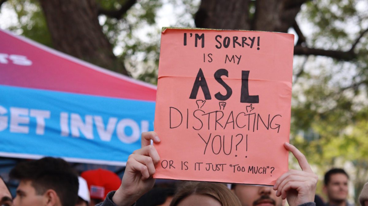 A CSUN student holds a sign that says "I'm Sorry! Is my ASL distracting you?! Or is it just "too much?" during Charlie Kirk's "The American Comeback Tour" visit on campus in Northridge, Calif., on Thursday, March 6, 2025.