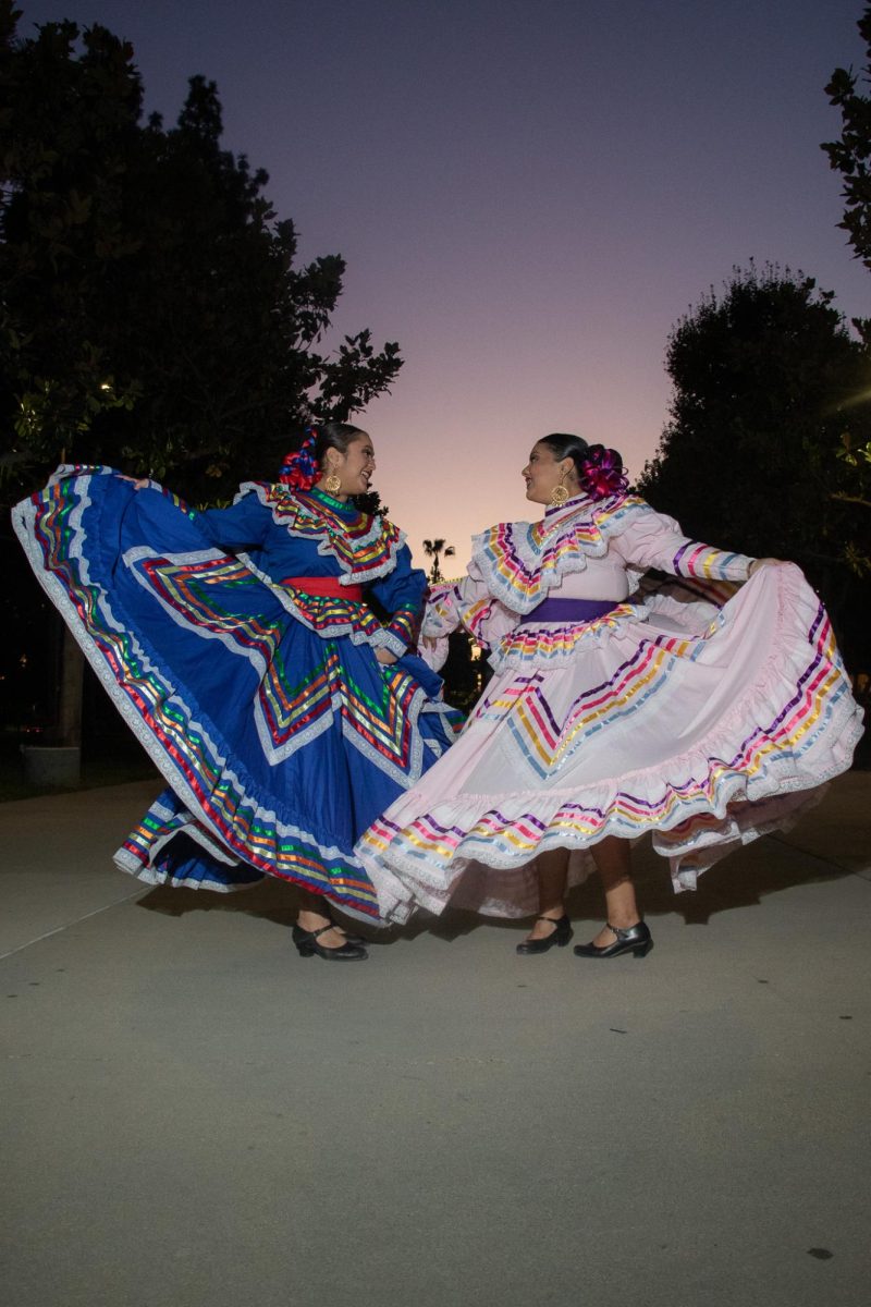 Presidenta del BFA de CSUN,Jazmín García y la vicepresidenta, Katelyn Casas bailan juntas con sus trajes folclóricos. (Fotografía de Claire Geriak)