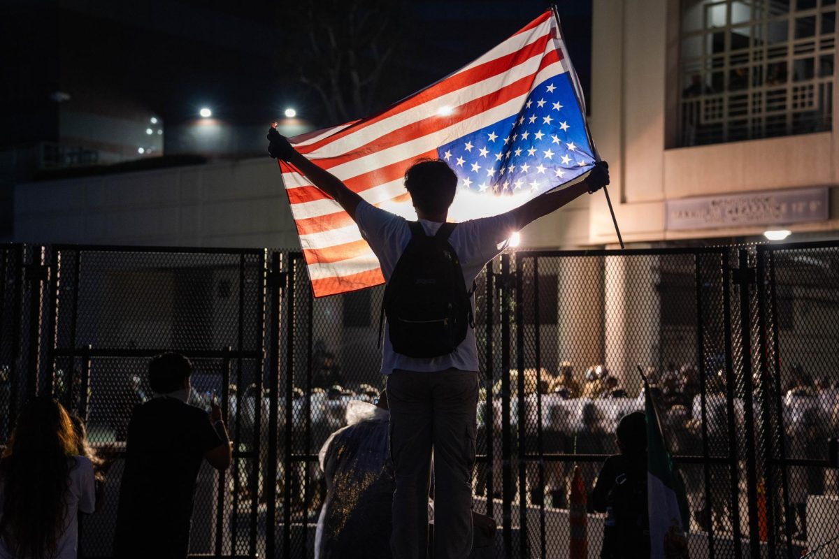 A protester waves an upside down American flag as Federal agents line up with riot shields outside the Federal Building on Sept. 1, 2025.