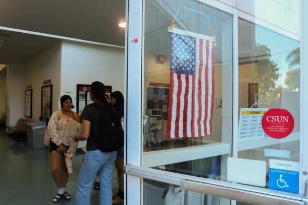 Andrea Muñoz standing in Redwood Hall outside of the voting center with friends in Northridge, Calif. on Oct. 29, 2025.