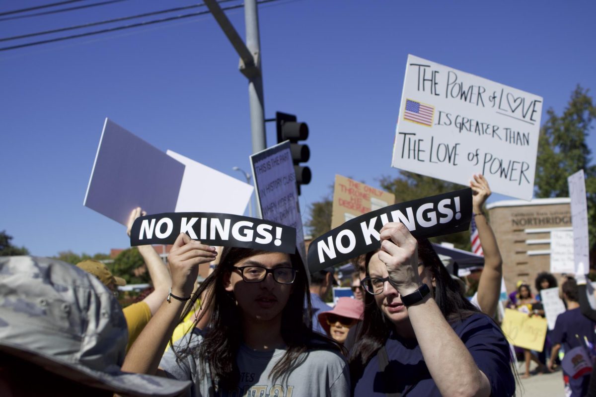 Los manifestantes sostienen carteles con el lema "¡No a los reyes!" a lo largo de Zelzah Avenue durante la protesta "No a los reyes" el 18 de octubre en Northridge, California.