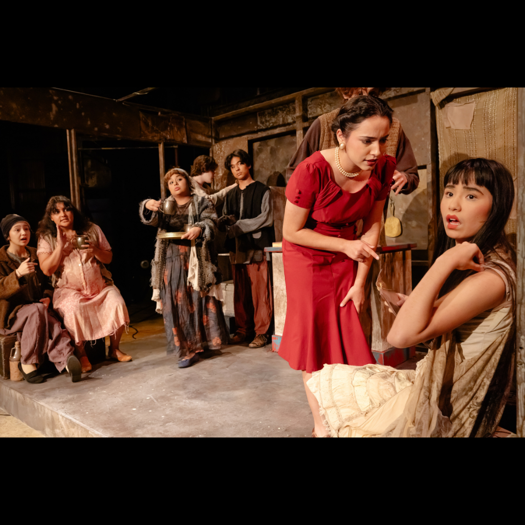 On the left in the tobacco shop is Maegan Fellner as Brother, and Laura Casillas as Sister-in-law. Next to them are Valerie Ramirez as Wife, Harry Gwillim as Carpenter, and Daniel Morgan as Nephew. To the right is Alexa Lara as the Landlady, pointing at Julia Sawyers as Shen Te, and behind Lara is Jackson Leighton as Husband. Photo courtesy of Brandon T. King