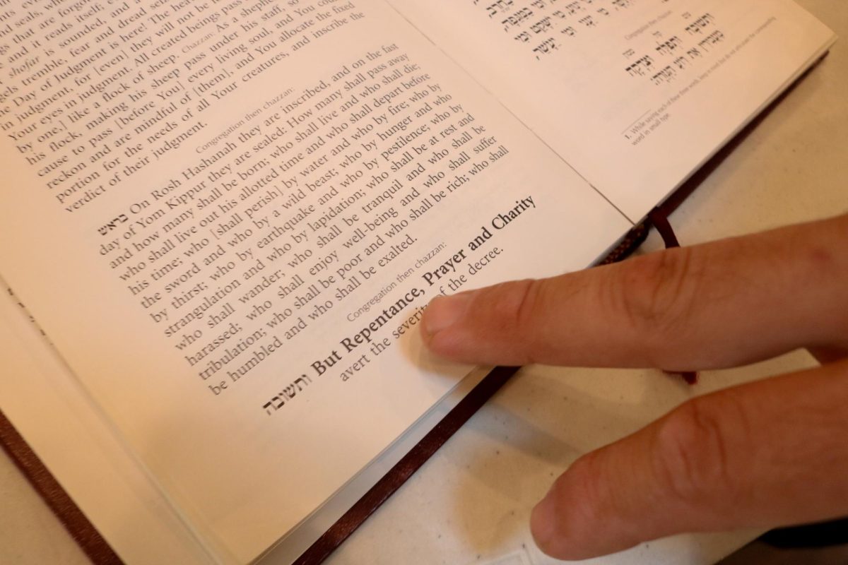 Rabbi Chaim Brook pointing to the verse "But Repentance, Prayer and Charity" in the Rosh Hashanah Machzor, a Jewish prayer book, on Sept. 30, 2025.