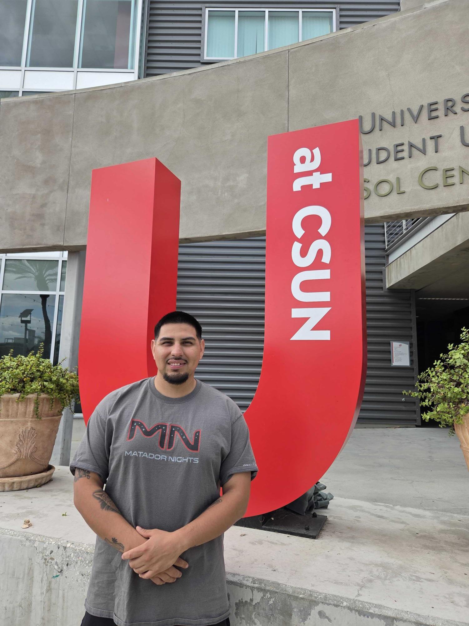Yoni Romero posa con alegría enfrente del edificio de USU en CSUN. Foto tomada por Ariadna Sánchez 4 de noviembre 2025.