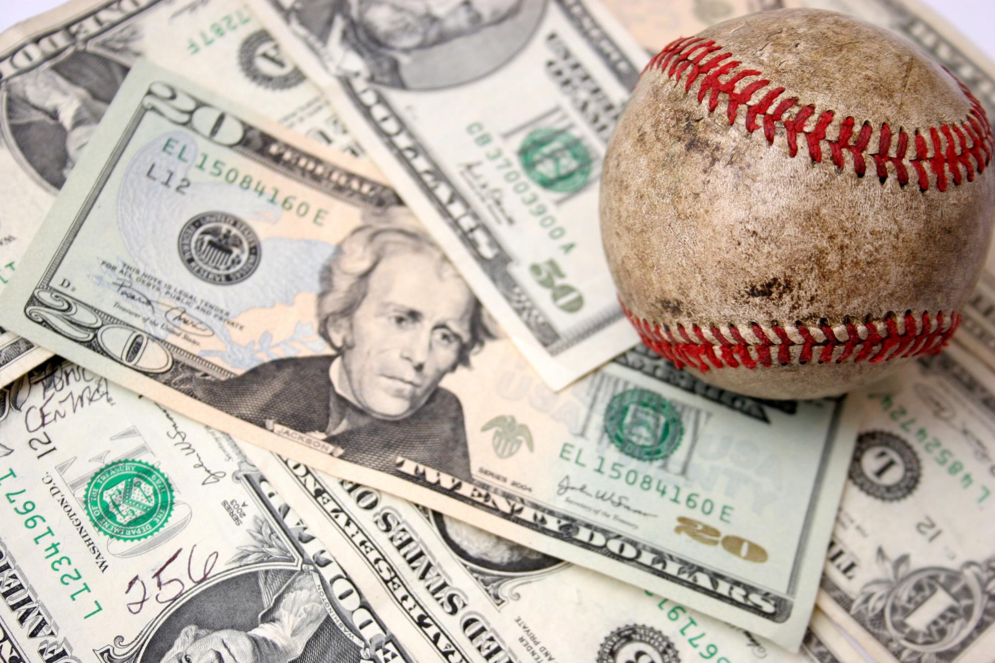 An image of a baseball sitting on top of $20 bills.