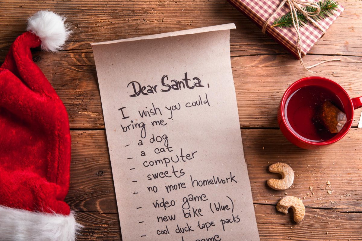 Photo of a wishlist for Santa alongside a mug of tea and cookies.