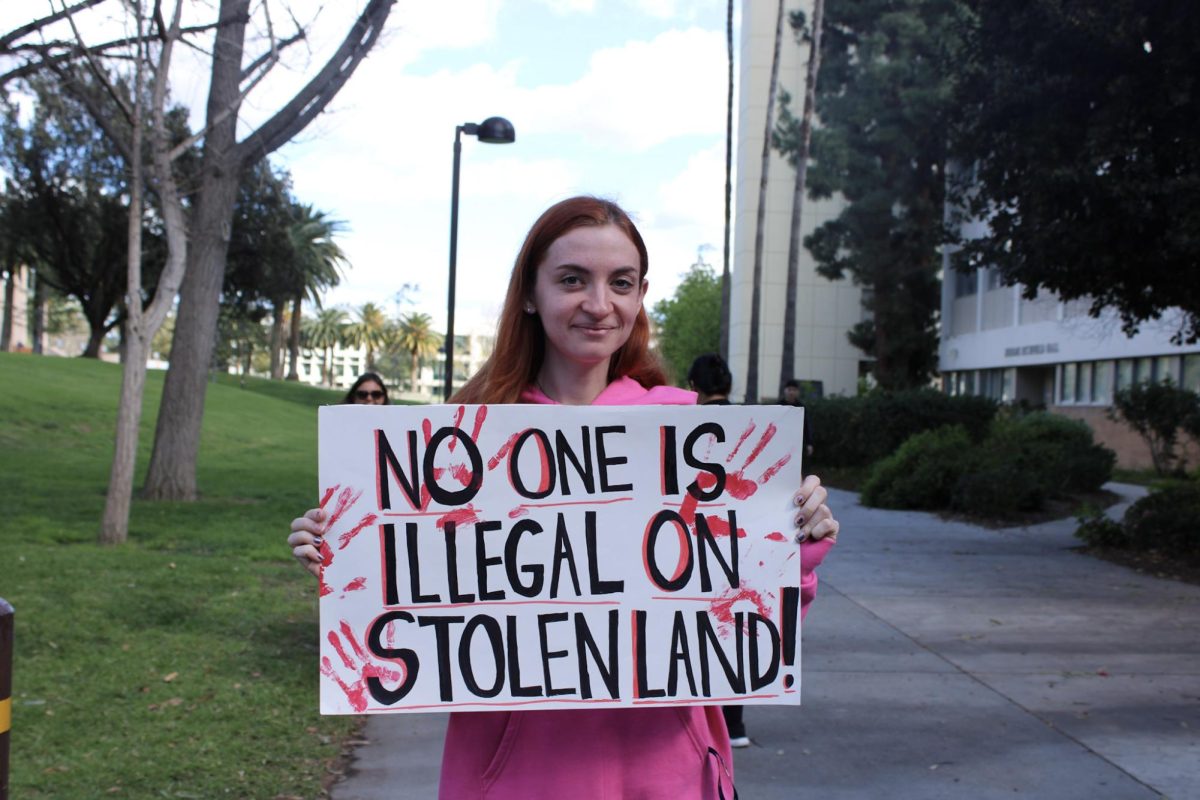 Student Michelle Giordano majoring in Sociology holds up a personal made sign that reads “No one is illegal on stolen land!” on Matador walk outside of Jerome Richfield building on February 18th, 2026.