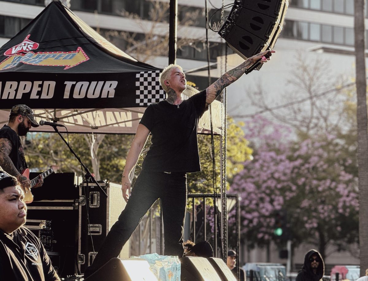 Travis Mills, lead vocalist of the band Girlfriends,  holds his microphone out to the crowd at the EZ-Sip Downtown Long Beach Block Party on Sunday, Feb. 1, 2026, in Long Beach, Calif. The event was a partnership between the Vans Warped Tour and the Downtown Long Beach Alliance.