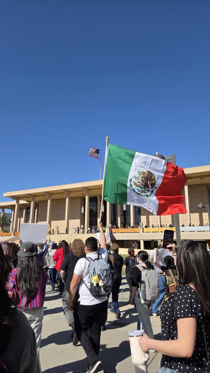 Un estudiante ondea con orgullo la bandera de México durante la protesta en CSUN contra las redadas migratorias.