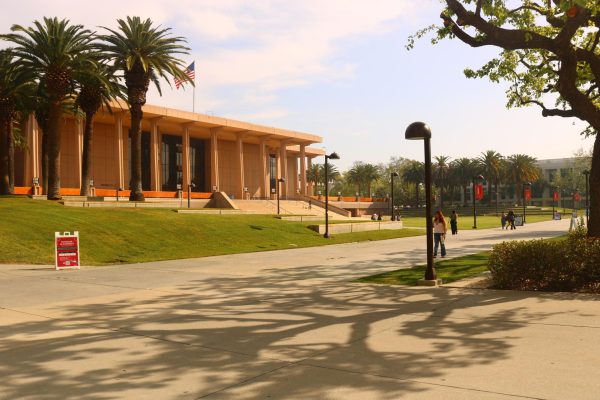 Students walk across the CSUN campus near the University Library during warm afternoon temperatures, highlighting the impact of heat on daily movement between classes. 