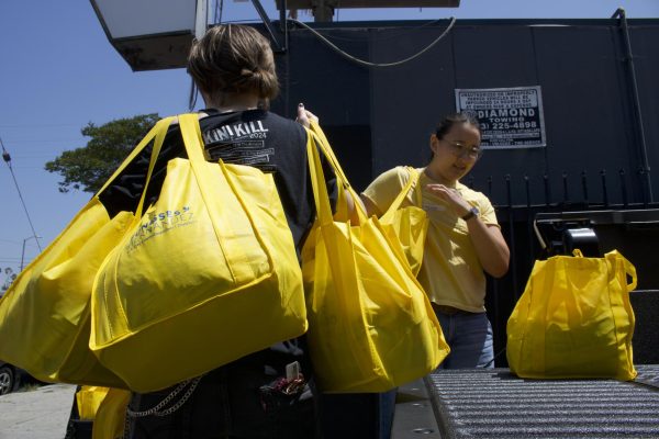 Volunteer Freddie Campbell helps carry in bags of food to The Offbeat bar in Highland Park, Los Angeles, Calif.