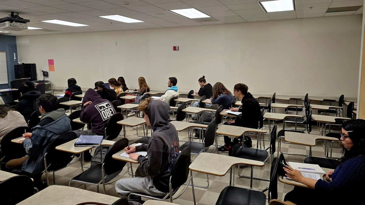 Students seated in a classroom taking notes during an in-person lecture at Manzanita Hall, Room #122 at CSUN. 