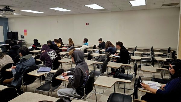 Students seated in a classroom taking notes during an in-person lecture at Manzanita Hall, Room #122 at CSUN.