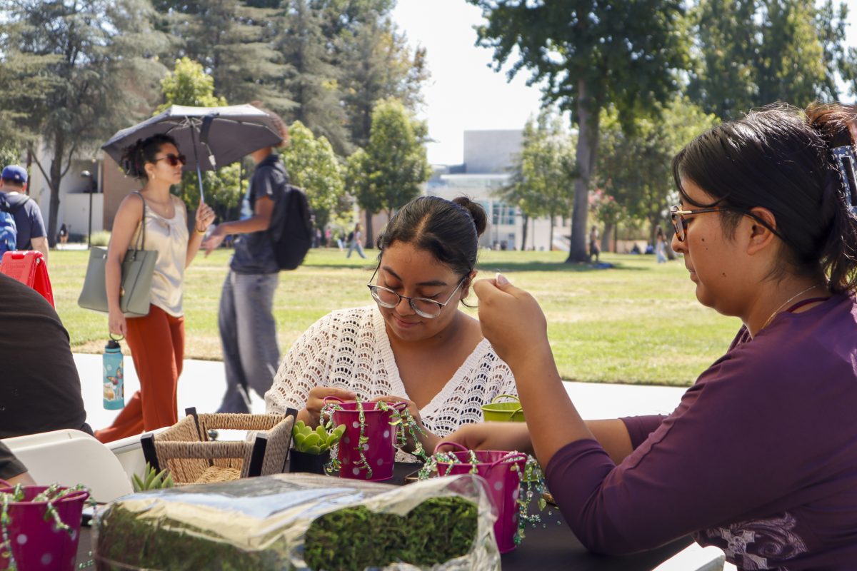 Kimberly Mendez and Allison Mendez participating in the sustainable crafting station creating beaded plants at the Campus Sustainability Day event in front of the University Library Lawn on Sept. 23, 2026.