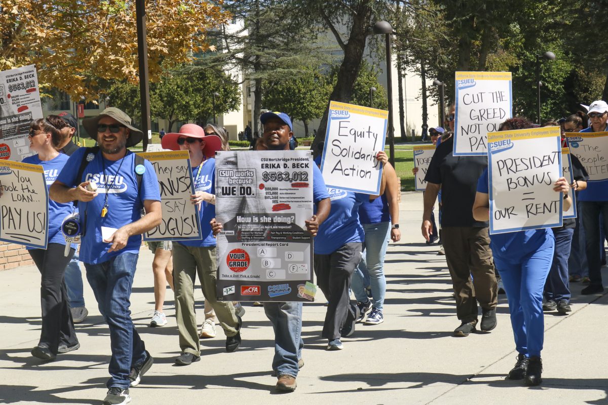 Protesters hold signs as they march during the CSUEU rally on September 30, 2026, in Northridge, Calif.